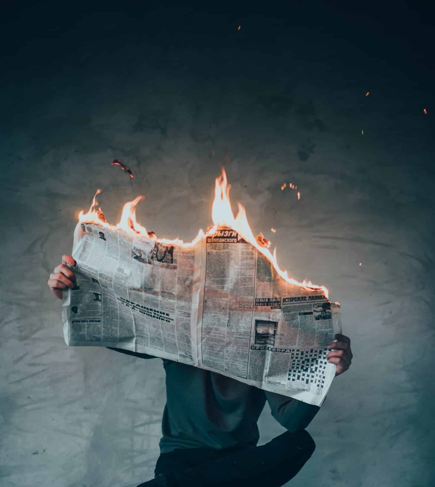 surrealism photography of person reading news paper in fire while sitting on stool
